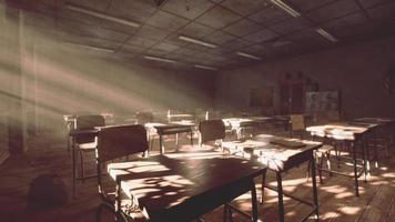 View to classroom with tables and small blackboard and grungy walls photo