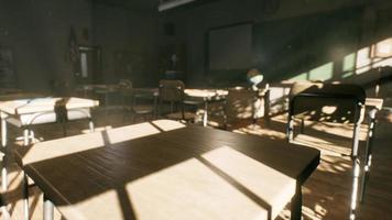 View to classroom with tables and small blackboard and grungy walls photo