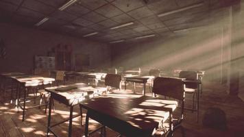 View to classroom with tables and small blackboard and grungy walls photo