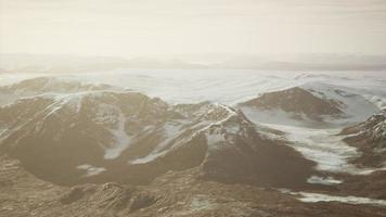 large snow patch left over on the volcanic rock field of a mountain in summer photo