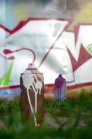 A few used paint cans lie on the ground near the wall with a beautiful graffiti painting. Street art and vandalism concept photo