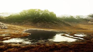 llanura con hierba seca y picos de montañas al fondo foto