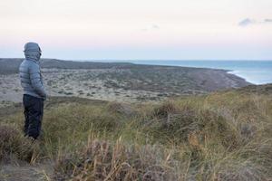 hombre mirando el amanecer rosa en la playa patagonia foto