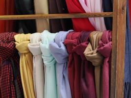 Colorful vintage scarfs with different patterns, colors and textures hanging on a rack at an outdoor shop photo