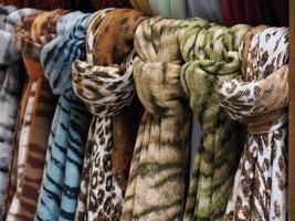 coloridas bufandas vintage con diferentes patrones, colores y texturas colgando de un estante en una tienda al aire libre foto