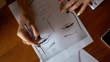 young girl draws eyebrows on a paper face silhouette video