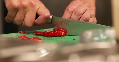 chef snijden rood pepers Aan een hakken bord gebruik makend van mes in de keuken van een restaurant. - dichtbij omhoog schot video