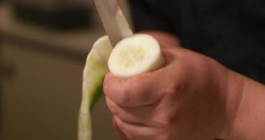 trancher le concombre frais pelé aligner la lame du couteau presque verticalement autour de lui préparer une feuille de concombre pour le rouleau de sushi. - photo en gros plan video