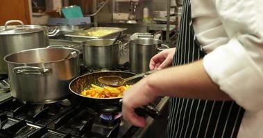 restaurant chef Koken heerlijk penne pasta recept in een pan gebruik makend van plastic pollepel - dichtbij omhoog, langzaam beweging video