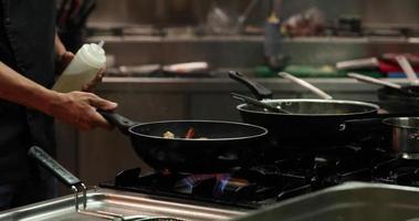 cuisine flambée - le chef qui jette et ajoute de l'alcool sur les fruits de mer cuits dans une poêle à frire crée une explosion de flammes dans la cuisine d'un restaurant. - Coup moyen video