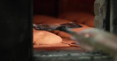 Baker Placing Sourdough Inside The Hot Oven With A Bread Peel For Baking - close up video