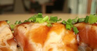 deliciosos rollos de sushi de salmón adornados con cebollino verde recién picado - macro video