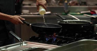 chef faisant flamber dans la cuisine d'un restaurant - chef jetant et versant du vin blanc sur les crevettes cuites sur une poêle à frire. - Coup moyen video