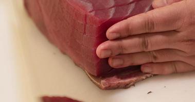 geschoold chef snijden een vers tonijn Aan een hakken bord in de keuken van een Japans restaurant. - dichtbij omhoog schot video
