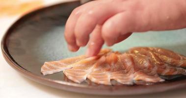 Anordnen von rohen Lachsfischscheiben in einem Teller - Sashimi-Zubereitung - Nahaufnahme video