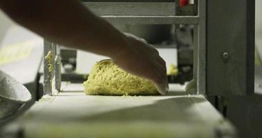 fazendo pão na padaria - mão do padeiro tirando a massa arredondada amarela crua do equipamento de rolamento da massa - close-up em câmera lenta video