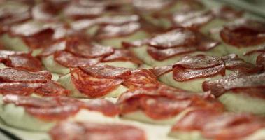 bröd deg med pepperonis på topp lägga på en bakning bricka i de bageri. - stänga upp, glidning skott video