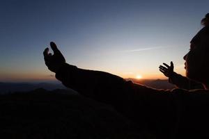 silueta de hombre cristiano rezando a mano, espiritualidad y religión, hombre rezando a dios. concepto de cristianismo. libertad y aventura de viaje. foto