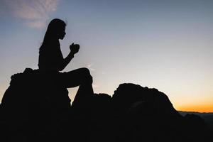 silueta de mujer cristiana rezando a mano, mujer rezando por la mañana en el fondo del amanecer. espiritualidad y religión, mujer rezando a dios. concepto de cristianismo. foto