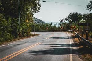 Curved paved road surrounded by green forest  travel driving environment backdrop background design template photo