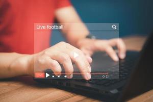 Man using a computer laptop for watching live football streaming online on virtual screen, searching video on internet, concept of content online. photo