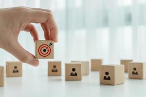 Hand holding dartboard target and team businessman icon on wood block. Teamwork goal and target planning. Business achievement and objective target. Team growing business success concept. photo