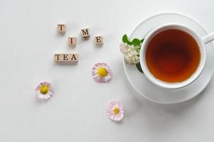 una taza de té sobre un fondo claro con flores y letras hora del té