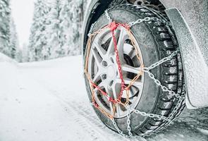 Snow chains on tire of car on snowy road in winter photo