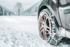 cadenas de nieve en el neumático en el camino nevado de invierno foto