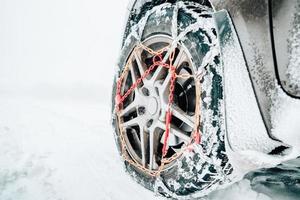 Snow chains mounted on a snowy car wheel photo