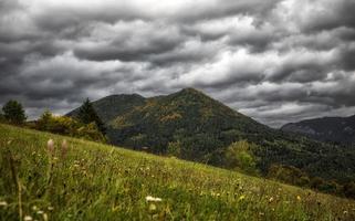 Stormy clouds on the sky over autumn country with meadow and hill at background photo