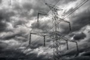 poste de alto voltaje y nubes oscuras en el cielo foto