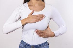 mano de mujer revisando bultos en su seno para detectar signos de cáncer de seno en un fondo gris. concepto de salud. primer plano de la mano de una mujer en el pecho que muestra un síntoma de cáncer foto