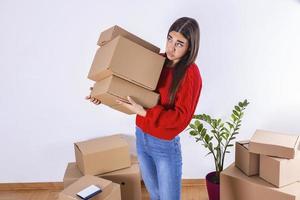 Young woman just moved in into new empty apartment unpacking and cleaning - relocation. Young girl carrying cardboard boxes at new home.Moving house. photo