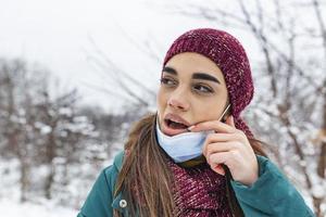 Don't touch your face, stop spreading Coronavirus. Young woman touching her mouth with dirty hand. Avoid touching your face. Woman putting down face mask rubbing her lip outdoor. photo