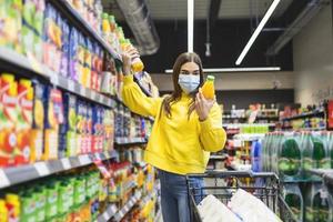 Person with protective face mask buying groceries supplies in the supermarket.Preparation for a pandemic quarantine due to coronavirus covid-19 outbreak photo