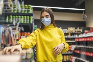 Woman wearing protective mask and buying food in grocery store during virus epidemic. young woman wearing a protective mask and gloves shopping in a time of virus pandemic, buying food supplies photo