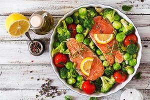 Raw salmon steak and vegetables for cooking on a light wooden background in a rustic style. Top view photo
