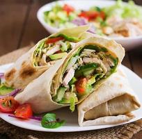 Fresh tortilla wraps with chicken and fresh vegetables on plate. photo