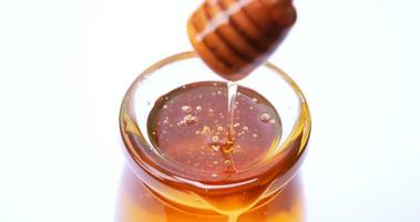 Close-up shot of dipping honey with a honey scoop in a glass bowl.