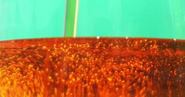 Close-up of engine oil pouring into a transparent container filled with tiny bubbles. video