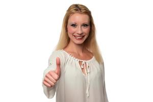 Enthusiastic motivated attractive young woman giving a thumbs up gesture of approval and success with a beaming smile photo