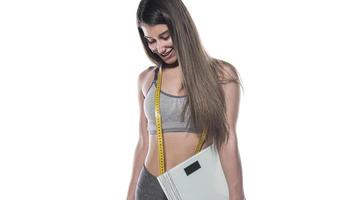 Happy slim woman satisfied with her diet results holding bathroom scales photo