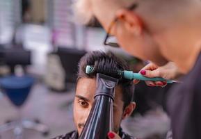 Professional hairdresser is cutting men's hair in beauty salon. photo