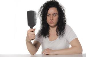 mujer joven tratando de peinarse el pelo rizado foto