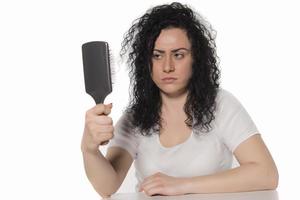 mujer joven tratando de peinarse el pelo rizado foto