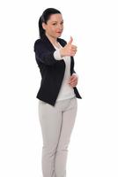 Happy business woman showing thumb up and looking at the camera over gray background photo