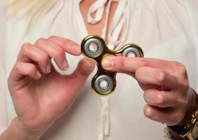 Girl to play with Fidget Spinner in his hands, the concept of relieving stress, develop a small hand mathematics. photo