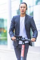 hombre de negocios asiático montando scooter eléctrico foto