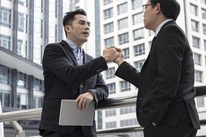 Successful negotiating business concept, Businessmen shaking hands after finishing meeting or setting  goals and planning way to success in front of building